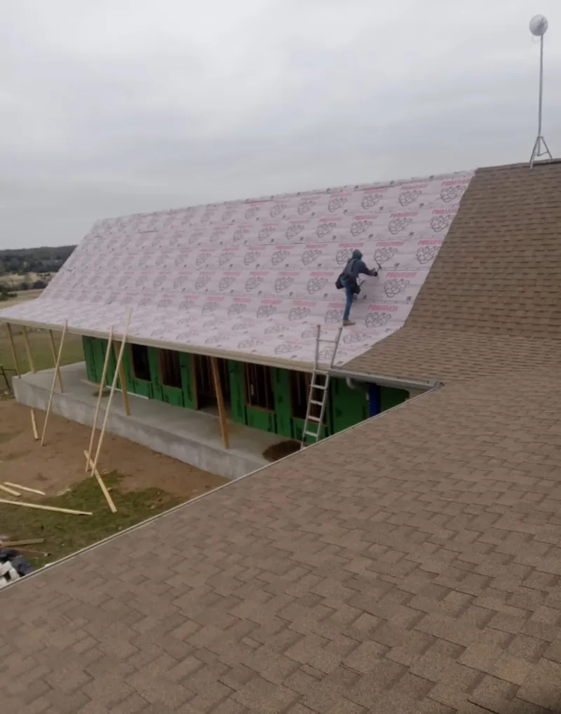 Worker preparing underlayment for a metal roof installation in Plantation